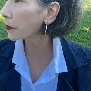 Large round silver post hoop earrings on woman in park